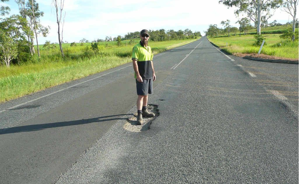 Shane Kelly standing in the pothole on the Bruce Hwy that almost claimed his life. Shane Kelly standing in the pothole on the Bruce Hwy that almost claimed his life.